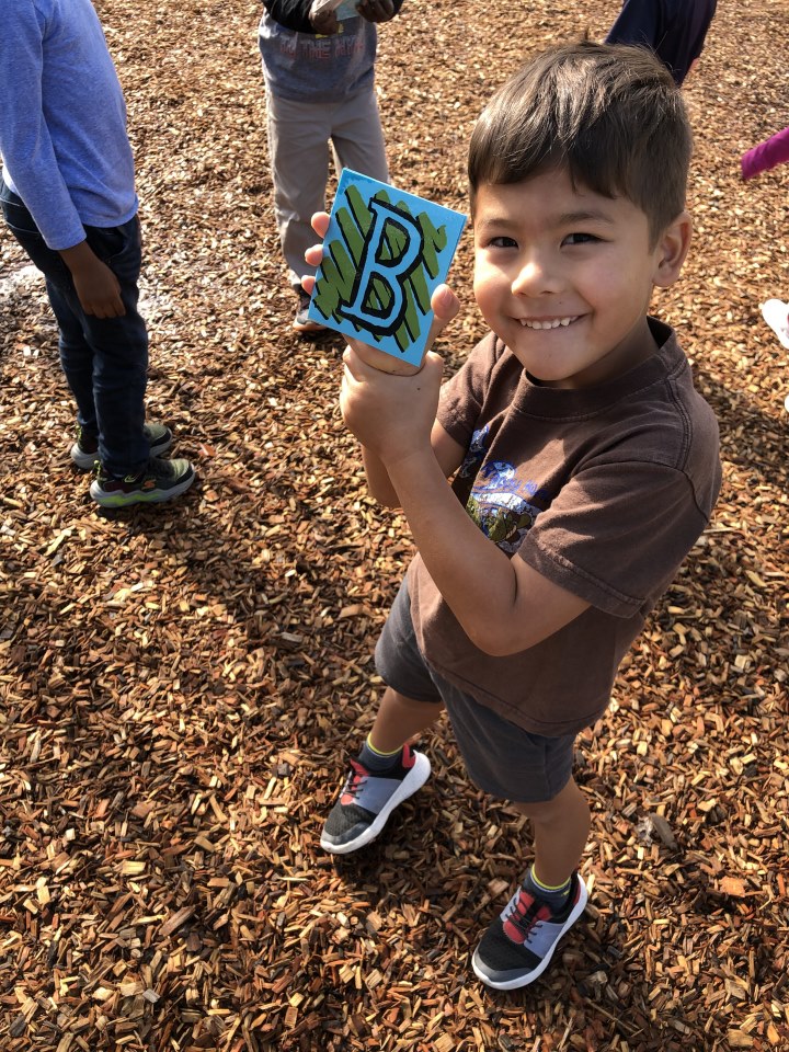 A preschool students finds letter B on the playground.