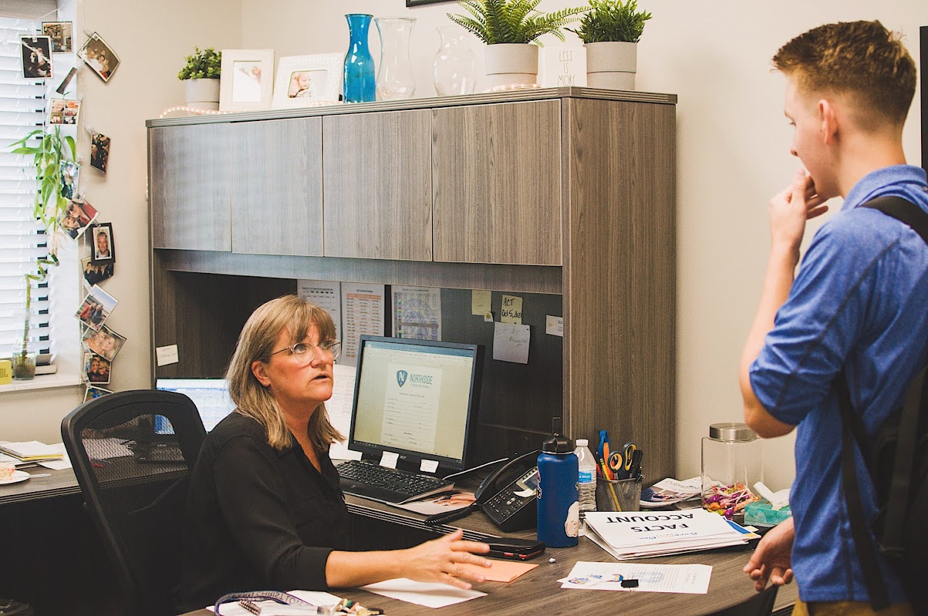 An office staff member greets a student.