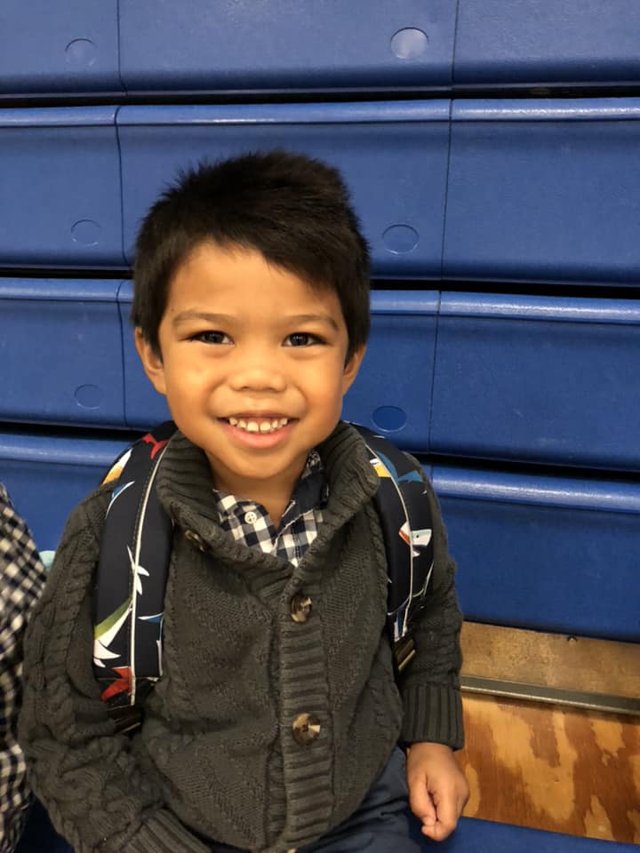 A smiling K4 student sits in the gymnasium